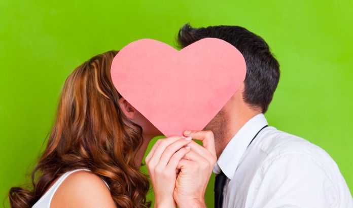 Young-couple-kissing-behind-heart-e1409842648703.jpg