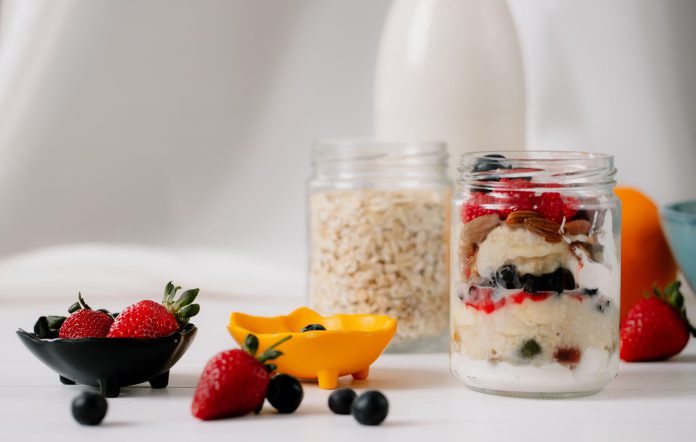 side-view-overnight-oats-with-fresh-strawberries-blueberries-nuts-glass-jar-rustic-table-scaled.jpg